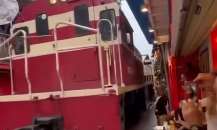 Viideo:Turistas extranjeros en mesas de un café en la Calle del Tren de Hanoi Vietnam mientras un tren pasa a escasos centímetros atracción controvertida donde las vías cruzan entre casas y locales comerciales. Autoridades locales evalúan reducir o eliminar el pa